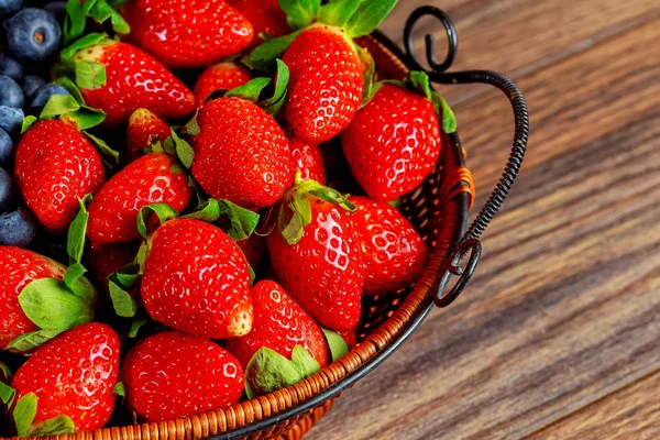 Bayas y fresas saludables en un fondo de madera canasta — Foto de Stock