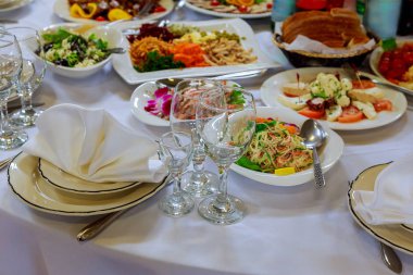 Ziyafet masasına servis edildi. Peçeteli, bardaklı ve salatalı şarap bardakları.