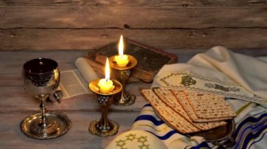 Şabat gümüş Birliği Kupası ve ahşap doku arka plan üzerinde iki yanan mumlar. Cam şamdanlar. Kırmızı şarap dökülen damlaları. Yahudi sabbath geleneksel nesneleri.