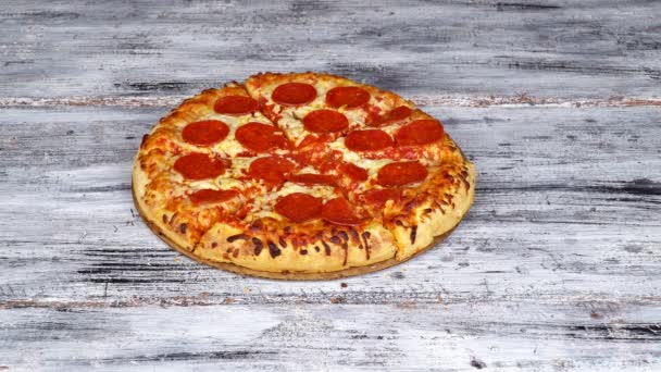 Рука крупным планом берет кусочек горячей вкусной итальянской пиццы из деревянной тарелки на фоне стола — стоковое видео