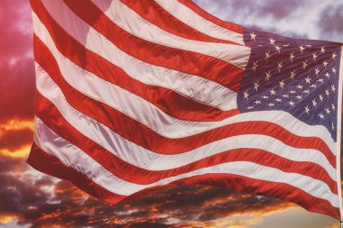 Güzel gün batımı güneşin doğuşu ile bulutlar, pembe ve mor tonları içinde üzerinde uçan Amerikan bayrağı