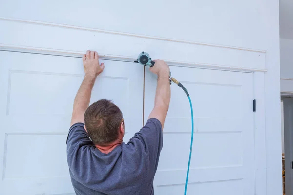 Carpinteiro brad usando pistola de prego para molduras em portas, moldando guarnição, com o rótulo de aviso de que todas as ferramentas elétricas — Fotografia de Stock