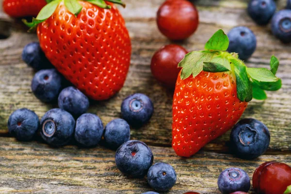 Arándanos Uva Fresas Frutas sobre plato de madera sobre fondo de madera — Foto de Stock