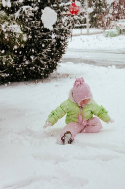 Komik küçük kız kar yağarken güzel kış parkında eğleniyor.