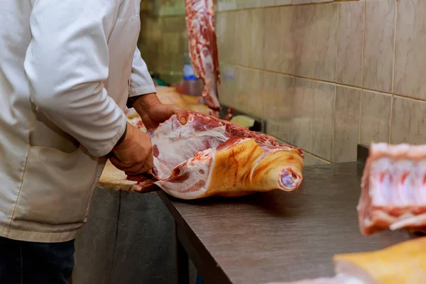 Cropped image of male butcher cutting raw meat with knife at counter in shop — Stock Photo, Image