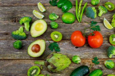 Yeşil smoothie ve malzemeler - avokado, elma, salatalık, kivi, limon, dereotu, kereviz, brokoli, ahşap tahta,