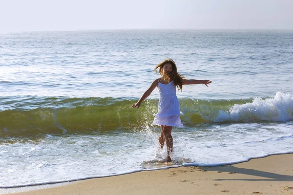 Menina bonita corre ao longo da praia em umas férias de verão — Fotografia de Stock