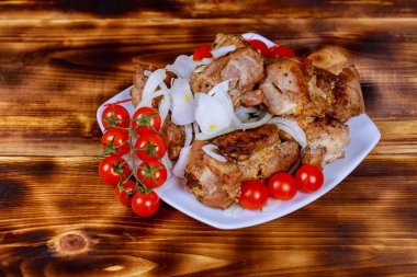 Ahşap yüzeyde tahtayı domuz eti şiş kebap olduğu barbecueand domates, soğan