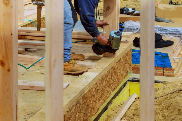 Stavební dodavatel pracovník s air hřebík zbraň hřebíkovačka pracuje na rohu horní desky zdí prvního patra — Stock fotografie