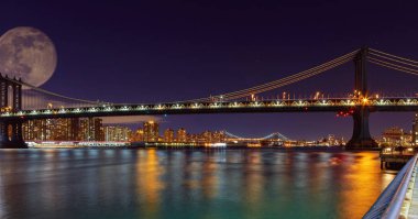 New York City'deki Manhattan Bridge Panorama adlı Manhattan siluetinin gece dolunay yükü ile aydınlatılmış. Dolunayda gezegen yörünge