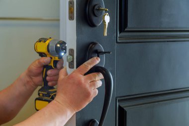 Closeup of a professional locksmith installing a new lock on a house exterior door with the inside internal parts of the lock clipart
