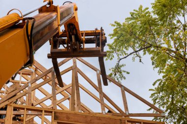Tahta bir çatı kirişinin çatıda bir kamyon forklifti tarafından kaldırılması yeni bir ev.