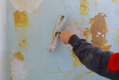 Erkek işçi duvar için macunun ilk katmanını kullanıyor.