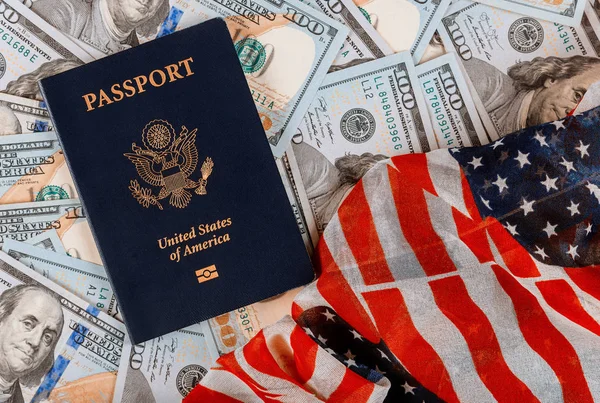 Pasaporte patriótico americano encima de una pila de cien monedas de billetes estadounidenses en la bandera estadounidense —  Fotos de Stock
