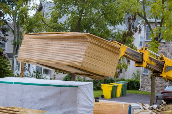 Heavy boom truck machinery is used to add the trusses to a timber frame house extension — Stock Photo, Image