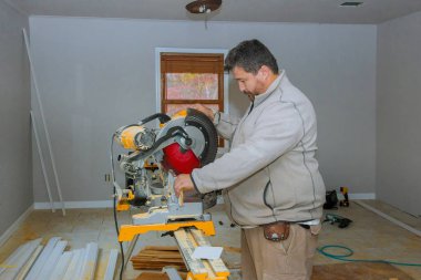 İşçi elektrikli testereyle tahta süpürgelik kesiyor.