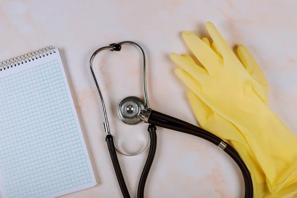 Стетоскоп на робочому столі лікаря в лікарні з медичними рукавицями і порожнім записником — стокове фото