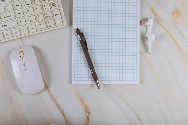 Lugar de trabajo con bloc de notas, auriculares inalámbricos y teclado de ordenador en fondo de mármol — Foto de Stock