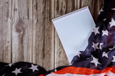 Tahta masa ve dalgalı Amerikan bayrağı arkaplanlı boş not kağıdının üst görünümü