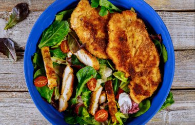 Eski ahşap arka planda taze sebzeler ile ızgara tavuk salatası.