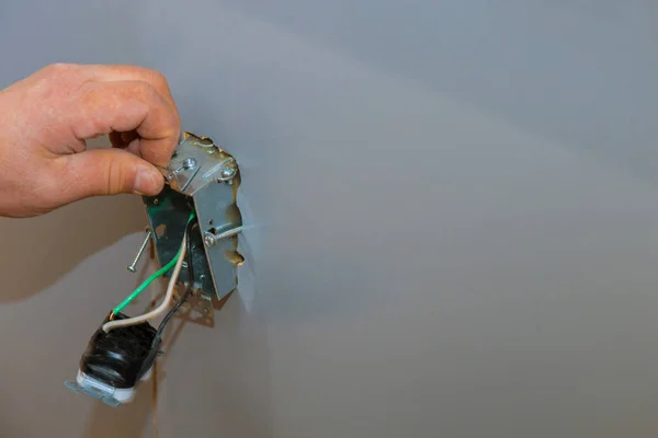 Установка электрических розеток в руке электрика, устанавливающего розетку — стоковое фото
