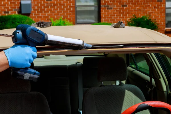 Глазир с помощью силиконовых инструментов ремонтирует лобовое стекло на замене лобового стекла автомобиля — стоковое фото