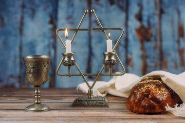 Tahta bir masa mumlar ve şarap fincan üzerinde challah ekmek ile Şabat.