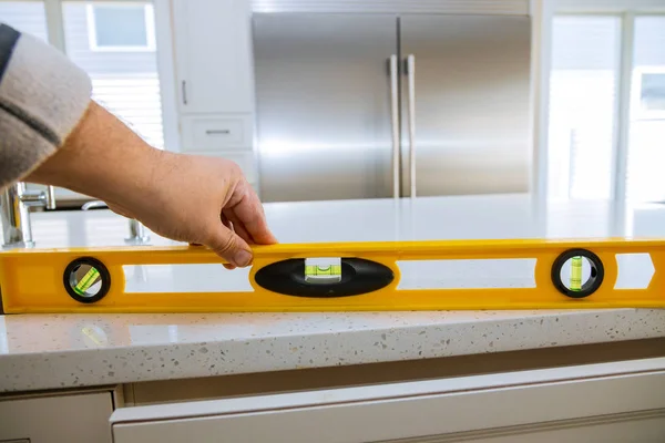 A worker checks the leveling of granite countertops in a home kitchen remodel — Stock Photo, Image