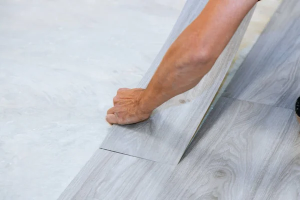 Trabajador instalación de piso de baldosas de vinilo nuevo piso de textura de madera laminada con nueva mejora del hogar — Foto de Stock