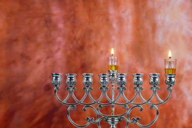 Lighting the first candle on a hanukkahof a burning Chanukah candlestick with candles Menorah clipart