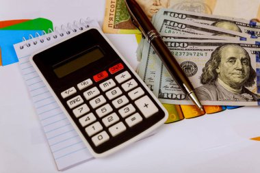 Hesap makinesi, dolar ve kalemi olan ofis masası.