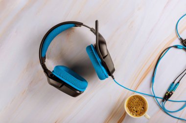 Kulaklıkla oynayıp kahve içerken mikrofon takıyor.