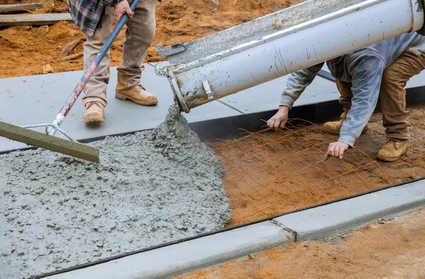 LKW-Fahrer gießt Betonguss auf Stahlstangen des Bürgersteigs — Stockfoto