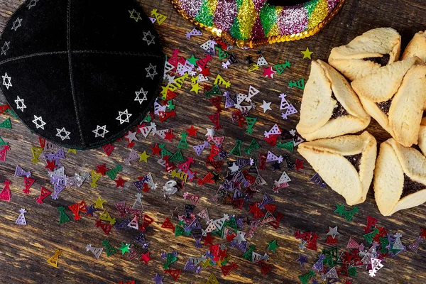 Fiesta judía Purim con hamantaschen galletas hamans orejas, máscara de carnaval y kippa, sobre fondo rústico —  Fotos de Stock