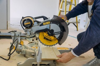 Dewalt dairesel testere işçisinin elektrikli testereyle tahta kesmesi, inşaat endüstrisi.