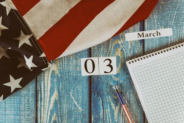 03月カレンダー日アメリカの旗自由と民主主義の象徴と空白のメモ帳とオフィスの木製のテーブルの上にペン — ストック写真