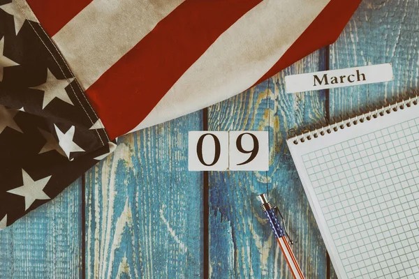 9 3月カレンダー日アメリカの自由と民主主義の象徴の旗と空白のメモ帳とオフィスの木製テーブルにペン — ストック写真