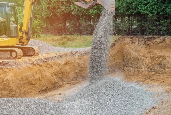 Excavator digging bucket scooping gravel from a building foundation — 스톡 사진