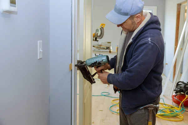 Interior de la construcción instalar la puerta nuevo carpintero de casa con pistola de clavos de aire — Foto de Stock
