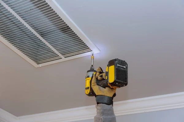 El hombre está instalando la cubierta de ventilación para el sistema de calefacción y refrigeración del hogar del techo — Foto de Stock