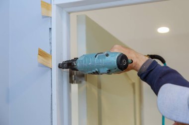 Havalı çivi tabancası kullanan işçiler iç kapıyı kuruyor.
