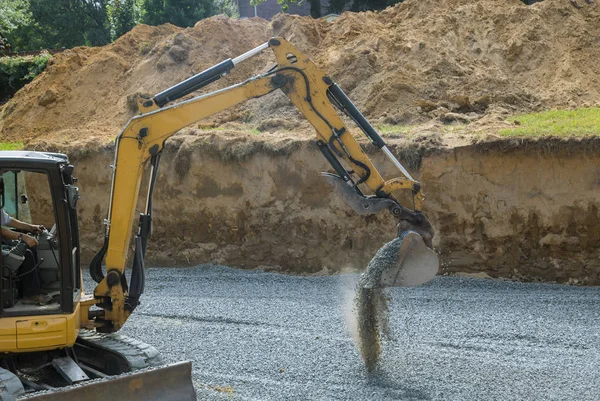 Excavadora con un cubo de pie sobre piedras de grava construcción de cimentación — Foto de Stock
