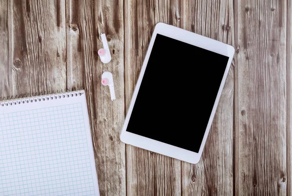 Üres fehér notebook, vezeték nélküli fejhallgató és digitális tabletta az asztalon — Stock Fotó