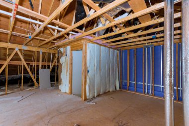 Yalıtım malzemesi ve boru ısıtma sistemiyle tavan arası yalıtımı çatı yapısının ahşap kirişleri.