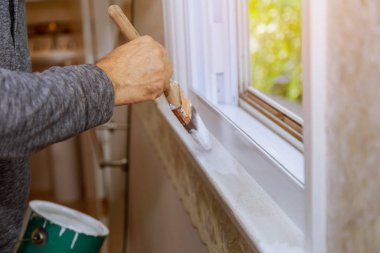 İşçi pencere çerçevesini beyaz renkle boyuyor