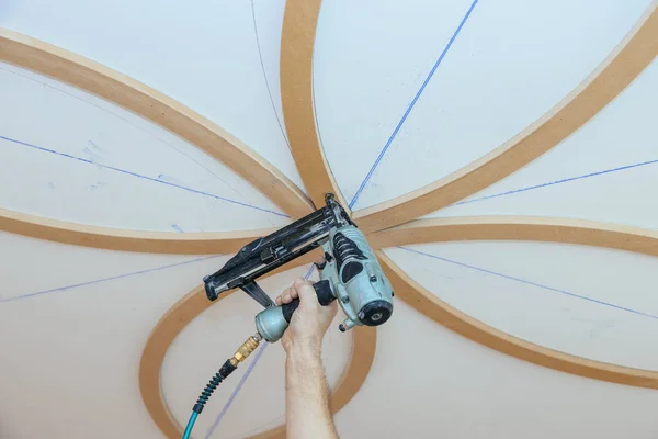 Installation of decorative mouldings on the ceiling carpenter using nail gun — Stock Photo, Image