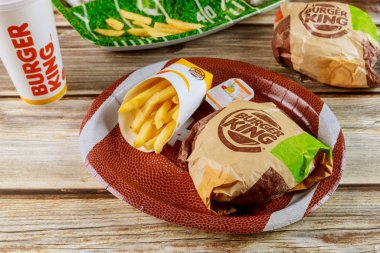 Burger King setindeki Super Bowl günü partisinde patates kızartması ve ahşap masa var.