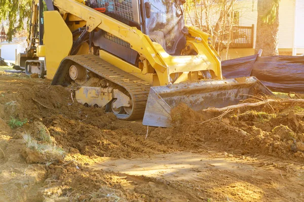 Mini excavadora que trabaja con tierra mientras hace trabajos de paisajismo en la construcción — Foto de Stock