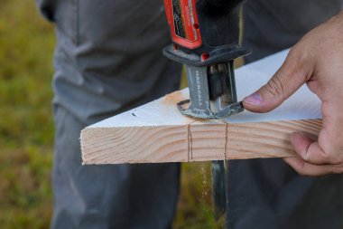 Milwaukee elektrikli aletleri kullanan adam tahta elektrikli testereleri kesiyor.