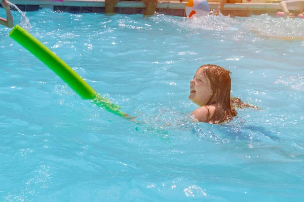 Girl swimming in pool water with stick. — Stockfoto